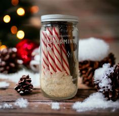 a jar filled with candy canes sitting next to pine cones