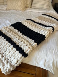 a crocheted blanket sitting on top of a bed next to pillows and blankets