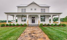 a large white house sitting on top of a lush green field next to a stone walkway