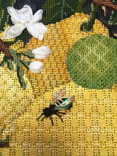 a bug sitting on top of a yellow table cloth next to white flowers and leaves