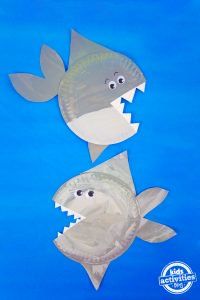 two paper plates shaped like sharks with their mouths open and teeth out, on a blue background