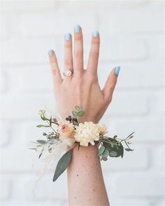 a woman's hand with blue fingernails and flowers on her wrist wearing a ring