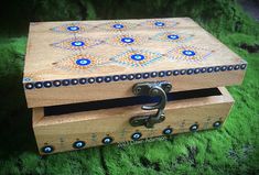 a wooden box with blue and orange designs on the lid is sitting in some green grass