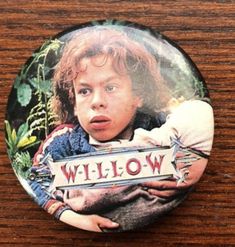 a close up of a button with a child holding a sign on it's chest