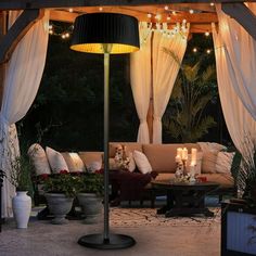 an outdoor living area is lit up with string lights and decorated in potted plants