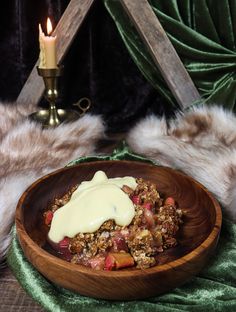 a wooden bowl filled with food next to a candle