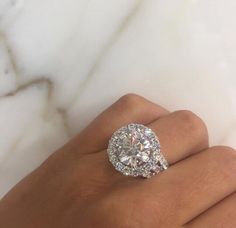 a woman's hand with a diamond ring on top of her finger and an oval shaped diamond in the middle