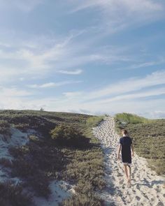 a man walking down a path in the sand