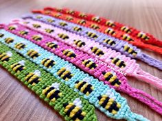 several crocheted bracelets are lined up on a wooden table, one is pink, the other is green and yellow