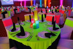 the tables are set up for an event with bright colors and black napkins on them