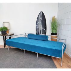 a blue futon bed sitting on top of a wooden floor next to a surfboard