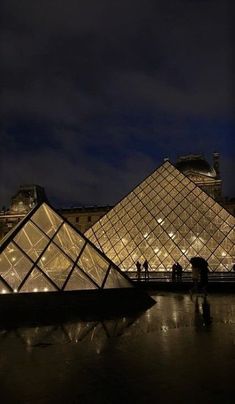 people standing in front of the pyramid at night