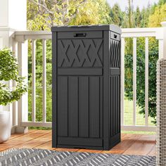 a black storage cabinet sitting on top of a wooden floor next to a planter