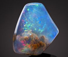 an opalite is shown on top of a black stand with other opals in the background