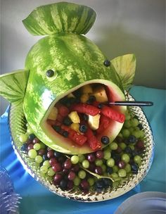 a fish made out of watermelon with grapes and other fruits in the mouth