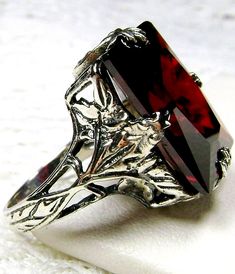 Garnet CZ Ring Description  GL Design#15 Made To Order Inspired by the Art Deco movement, I now offer this stunning Antique reproduction in antiqued sterling silver. This lovely ring is set with a 10ct flawless garnet CZ gemstone. The inside of the band is hallmarked 925. This rectangle-cut red garnet CZ is 16mm (5/8th of an inch) by 12mm (1/2 inch) in size. Notice the beautiful floral leaf design of the silver filigree setting and band... simply stunning. This is an exquisite rendition of an an Leaf Filigree, Art Deco Filigree, Star Garnet, Gemstone Art, Art Deco Movement, Order Design, Gems Art, Gothic Rings, Lovely Ring