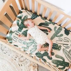 a baby sleeping in a crib with cactus print