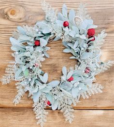 a christmas wreath with red berries and greenery on a wooden background, top view