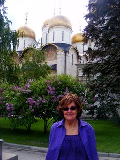 a woman standing in front of a large building with domes on it's sides