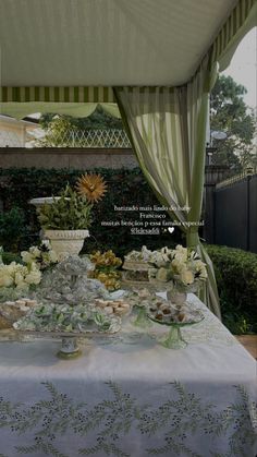 a table covered in white flowers and plates with food on it, under a canopy