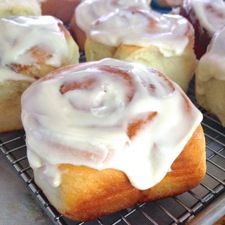 cinnamon rolls with icing sitting on a cooling rack