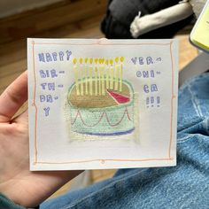 a person holding up a card with a birthday cake on it