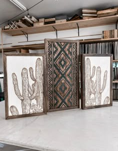 three framed artwork pieces with cactus designs on them in a room filled with bookshelves