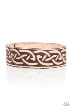 a brown and black bracelet with an intricate design on the inside, sitting on a white surface