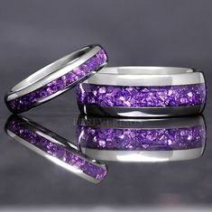 two wedding bands with purple stones in them on a reflective surface, one is silver and the other is white gold