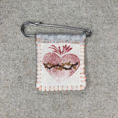 a small piece of cloth with a heart and two birds on it hanging from a hook