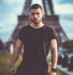 a man standing in front of the eiffel tower with his hand on his hip