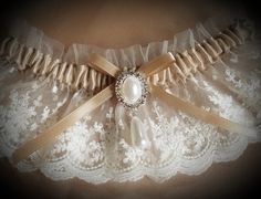 This vintage look garter is lovely in light ivory net lace over a champagne satin band. Decorated with a faux pearl and crystal finding. This garter is also available in plus size, just convo me with questions or your own design ideas! A blue satin rolled rose can be added to the inside of the band for your 'something blue'. Packaged in a view-top box tied with an elastic metallic bow, perfect for gift-giving or for safe-keeping after the wedding. Elegant Cream Lace For Wedding, Elegant Cream Lace For Bride, Elegant Beige Lace For Wedding, Fitted Cream Lace For Ceremony, Cream Fitted Lace For Ceremonies, Fitted Cream Lace For Wedding Night, Fitted Classic Lace For Wedding, Classic Fitted Lace For Wedding, Cream Lace For Wedding Night