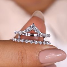 a woman's hand holding two wedding rings with diamonds on each one and the other