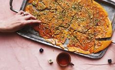 a pizza sitting on top of a pan covered in toppings next to a knife and fork