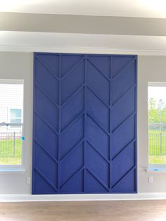 a blue door in the middle of a room with wood flooring and white walls