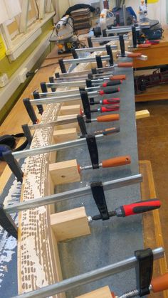 many different types of tools are lined up on a table in a room with wood flooring