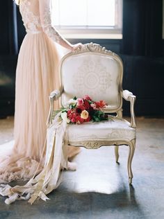 an image of a woman in a dress standing next to a chair with flowers on it