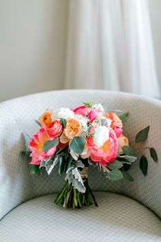 a bridal bouquet sitting on top of a white chair