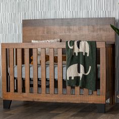 a baby crib with an elephant blanket on top of it next to a potted plant