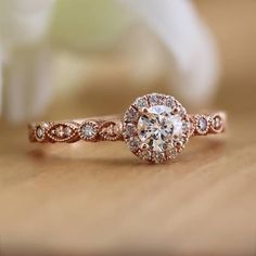 a close up view of a diamond ring on a wooden surface with flowers in the background