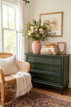 a living room with a green dresser and flowers in a vase on top of it