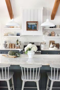 three white chairs sit at the center of a kitchen island