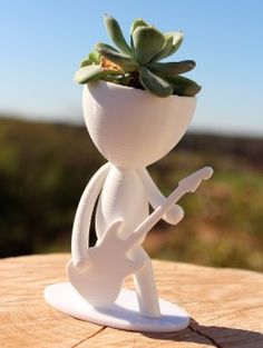 a white ceramic figurine holding a plant on top of a wooden table with blue sky in the background