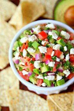 a white bowl filled with salad next to tortilla chips