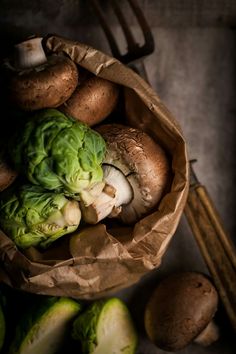 some vegetables are sitting in a paper bag next to mushrooms and other foodstuffs