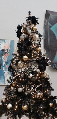 a black and white christmas tree with ornaments on it in front of a blue wall