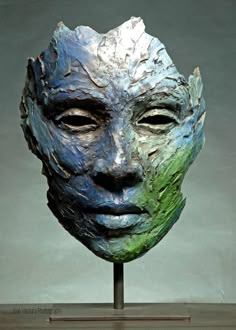 a sculpture of a man's face with green and blue paint on it