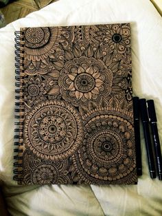 a notebook and pen sitting on top of a white sheet with an intricate design in the middle