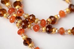 Incredibly luxurious, this stunning necklace captures the attention of all who gaze upon it. Rich carnelian beads, matte Gold Rondelles, brown Chinese crystal and Swarovski© crystal, and a tribal matte gold medallion offset one another in an exquisite symphony of beauty. This long necklace is perfect for highlighting any outfit, from casual chic to festive elegance. Elegant Gold Carnelian Beaded Necklaces, Elegant Gold Carnelian Beaded Necklace, Elegant Brown Carnelian Necklace, Elegant Amber Necklace With Gold Beads, Elegant Orange Czech Glass Jewelry, Elegant Orange Beaded Crystal Necklace, Elegant Orange Carnelian Beaded Necklace, Gold Carnelian Jewelry With Faceted Beads, Elegant Orange Necklace With Spacer Beads