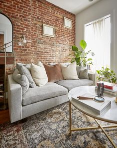 a living room filled with furniture and a brick wall